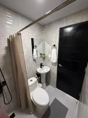 a bathroom with a toilet and a sink and a black door at Moon Apartamentos C4 in San Cristóbal