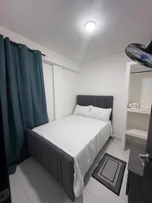 a small bedroom with a bed with green curtains at Moon Apartamentos C1 in San Cristóbal