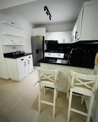 a kitchen with white cabinets and a table and chairs at Residencial ambar lll in Santiago de los Caballeros