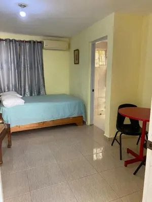 a bedroom with a bed and a table and a door at Nido del patio, 40 min to Bocachica beach 5 center in La Piedra