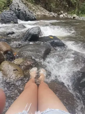 a pair of legs laying on rocks in a river at Casa campo Ana Victoria