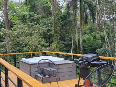 a hot tub on a deck with a grill at Cabaña Silencio Verde in Jarabacoa