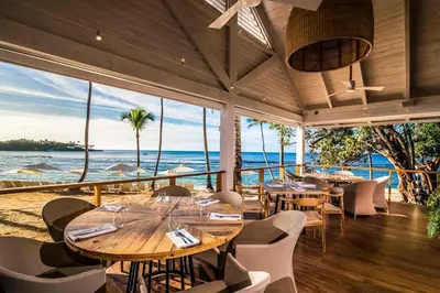 a restaurant with tables and chairs and a view of the ocean at Luxury 3BR Penthouse in Casa de Campo, Gated Resort Living & Golf View in La Romana