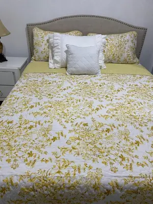 a bed with a yellow and white bedspread with yellow flowers at ajmicasita in Constanza