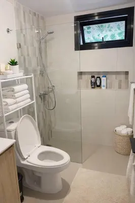 a bathroom with a toilet and a shower with a window at Mountain and pool modern apartment in Santiago de los Caballeros