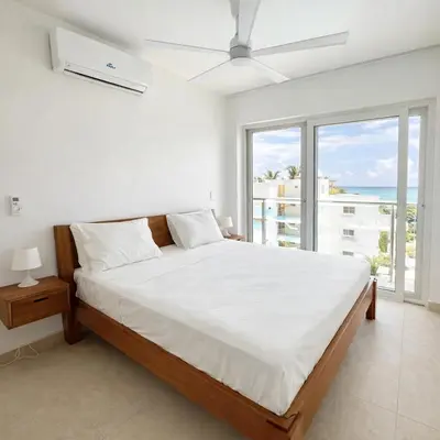 a white bedroom with a bed and a large window at Sunset Calm Penthouse in Cabarete