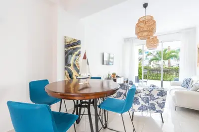 a dining room with a wooden table and blue chairs at Coastal Corner -Beach-Pool-Terrace-Parking-Pets in Villas del Mar