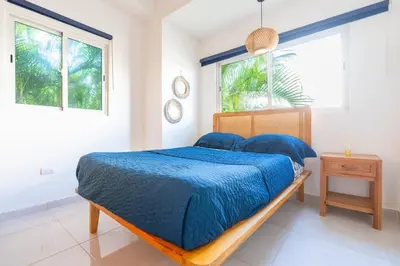 a bedroom with a bed with blue comforter and two windows at Coastal Corner -Beach-Pool-Terrace-Parking-Pets in Villas del Mar
