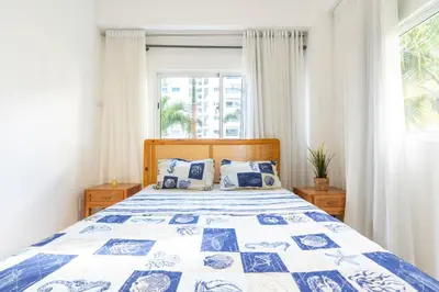 a bedroom with a blue and white bed with a window at Coastal Corner -Beach-Pool-Terrace-Parking-Pets in Villas del Mar