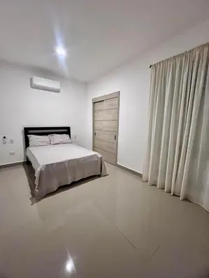 a white bedroom with a bed and a window at Laggo one houses in Punta Cana