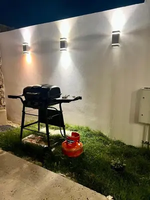 a grill sitting in the grass next to a wall at Laggo one houses in Punta Cana