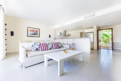 a living room with a white couch and a table at Iberostate 2BR Apartment - BBQ, Terrace, Lake & Golf Views, Beach Club Access in Punta Cana