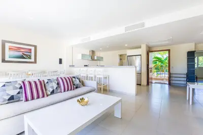 a living room with a white couch and a table at Iberostate 2BR Apartment - BBQ, Terrace, Lake & Golf Views, Beach Club Access in Punta Cana