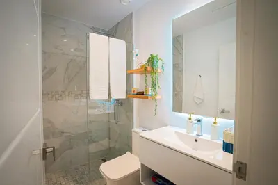 a white bathroom with a sink and a shower at Golf View Penthouse with Private Rooftop & BBQ in Punta Cana