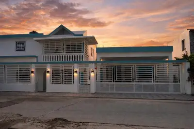 a white house with a sunset in the background at Apartamentos carrasco in Nagua