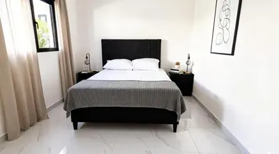 a white bedroom with a bed with a black headboard at Villa Brisa Marina in Boca Chica