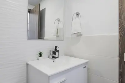 a white bathroom with a sink and a mirror at Nestled Comfort in 1BR -WeHost DR in Santo Domingo