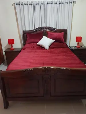 a large wooden bed with red sheets and red pillows at My house 56 in San Francisco de Macorís
