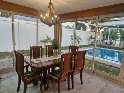 a dining room with a table and chairs and a pool at Oceanfront villa with pool, Ocoa bay in Azua
