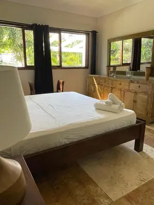 a large bed in a room with two windows at Villa exotic in Juan Dolio