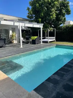 a blue swimming pool in front of a house at Villa exotic in Juan Dolio