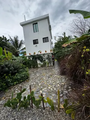 a white house with a stone walkway in front of it at Monte y Cielo 1 apartment in Las Galeras