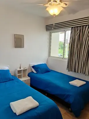 a bedroom with two blue beds and a window at Residencias Turísticas Espinosa in Villas del Mar