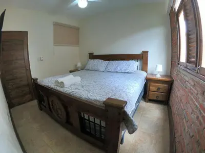 a bedroom with a bed with a wooden frame and a window at Villa 3 Habitaciones con piscina in Jarabacoa