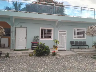 a white house with two chairs in front of it at Brisa del mar in Boca Chica