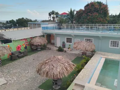 a house with a swimming pool and some straw umbrellas at Brisa del mar in Boca Chica