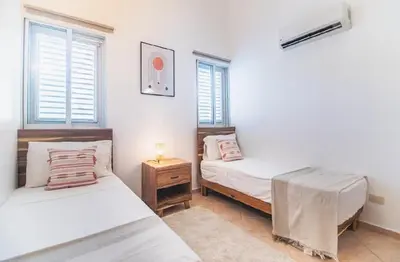 a bedroom with two beds and a nightstand and two windows at Cultrera 1 in Las Terrenas