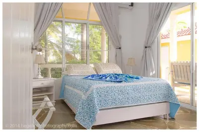 a bedroom with a bed with a blue blanket and a window at Villa Dawn, Bahia de Arena in Cabarete