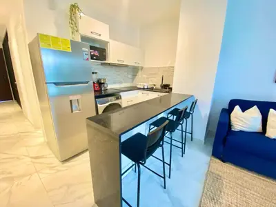 a kitchen with a counter with chairs and a refrigerator at 1B Fantasy Lodge @t Canabay Private Pool and beach in Punta Cana