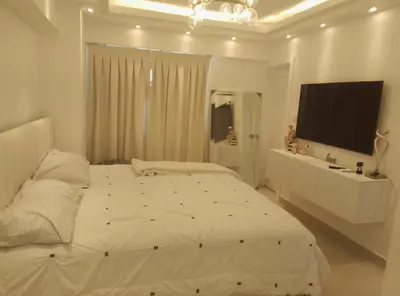 a white bedroom with a large bed and a television at Sky 01 M10 in Santo Domingo