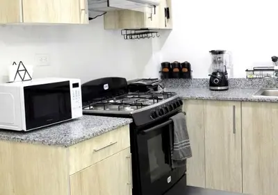 a kitchen with a black stove and a microwave at Comfy & Secure Modern 2BR Apartment just 5 minutes from Airport in Boca Chica in Boca Chica