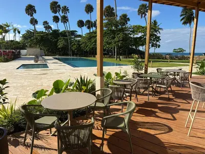 a patio with tables and chairs and a pool at Stunning oceanfront apartment in Encuentro at The Wave in Cabarete