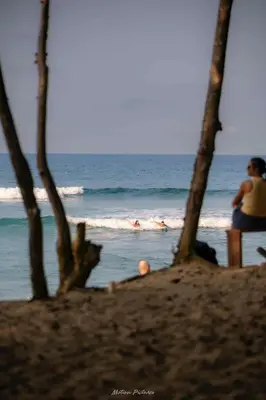 a person sitting on a beach looking at the ocean at Stunning oceanfront apartment in Encuentro at The Wave in Cabarete