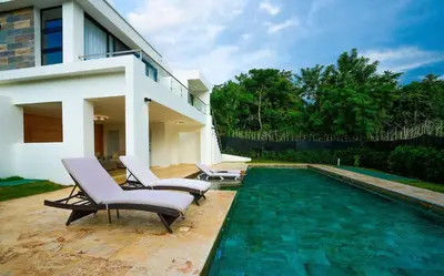 a swimming pool with two chairs and a house at Modern Villa with a 15m Lap Pool, Cabarete in Cabarete