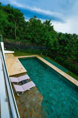 a swimming pool with two white chairs in the water at Modern Villa with a 15m Lap Pool, Cabarete in Cabarete