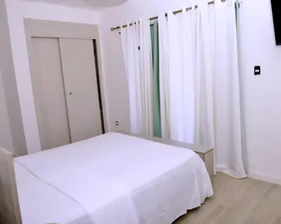 a white bed in a room with white curtains at Peaceful 2BR Retreat with Pool, Paddle Court & Private Beach Access in Punta Cana