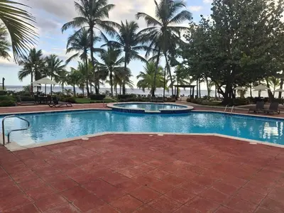 a swimming pool with palm trees in the background at Apartment facing the Caribbean Sea, Juan Dolio Beach in Juan Dolio