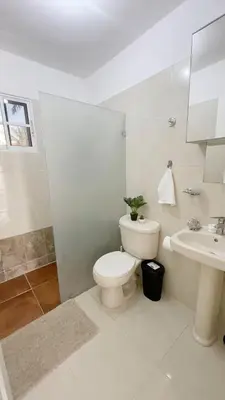 a white bathroom with a toilet and a sink at Cozy 2BR 2Bth walk 2 the beach Pool view Wi-Fi in Punta Cana