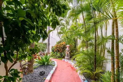 a garden with palm trees and a red pathway at Cozy 2BR 2Bth walk 2 the beach Pool view Wi-Fi in Punta Cana