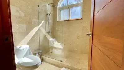 a bathroom with a toilet and a glass shower at Luxury 2BR Villa - Beach Access and Elegant Design at Cabarete in Cabarete