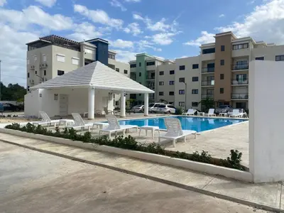 a swimming pool with chairs and a gazebo at Apartmento en Caleta, La Romana in La Romana