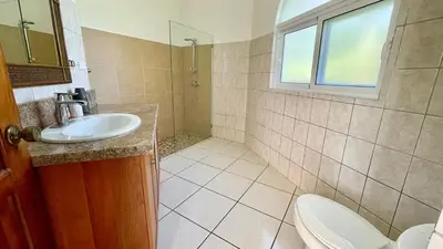 a bathroom with a sink and a toilet and a window at 2BR villa & 1BR Guest House, Pool and Beach at Playa Encuentro, Cabarete in Cabarete