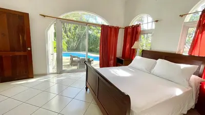 a bedroom with a bed and a large window at 2BR villa & 1BR Guest House, Pool and Beach at Playa Encuentro, Cabarete in Cabarete