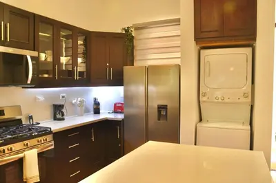 a kitchen with wooden cabinets and a stainless steel refrigerator at Beachfront Hideaway 2BR Apartment at Playa Encuentro, Cabarete in Cabarete