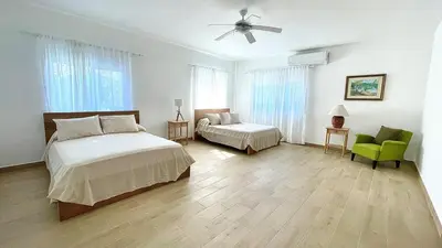 a bedroom with a bed and a couch and a fan at 3BR Hideaway Lux Villa With Pool & beach Access At Playa Encuentro, Cabarete in Cabarete