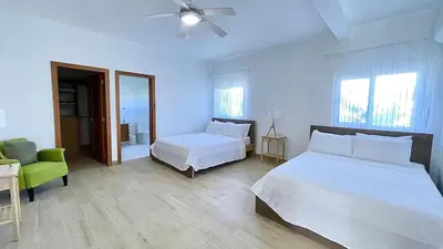 a bedroom with two beds and a green chair at 3BR Hideaway Lux Villa With Pool & beach Access At Playa Encuentro, Cabarete in Cabarete